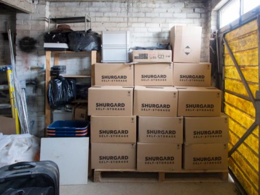 Moving boxes stacked on a pallet in a brick garage